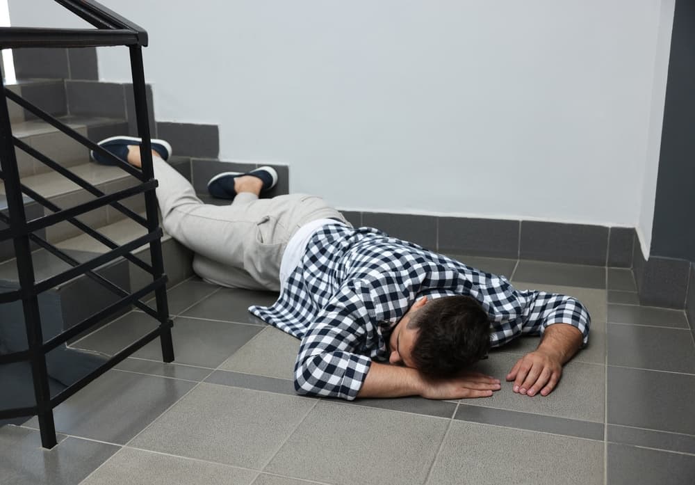 Unconscious man lying on the floor after falling down indoor stairs.