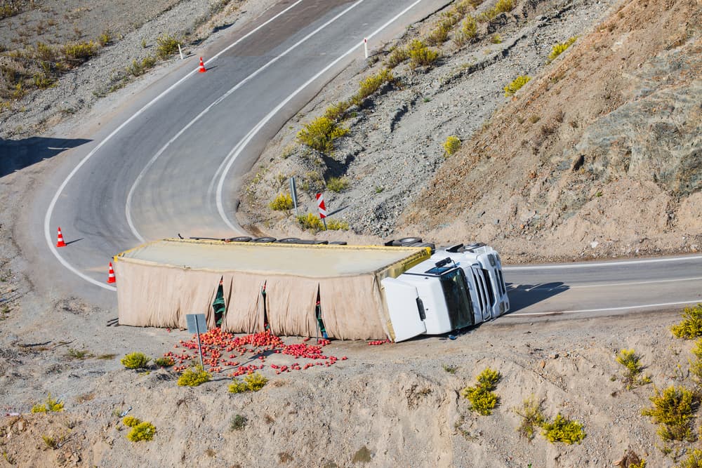 The truck is overturned on the road after the accident.

