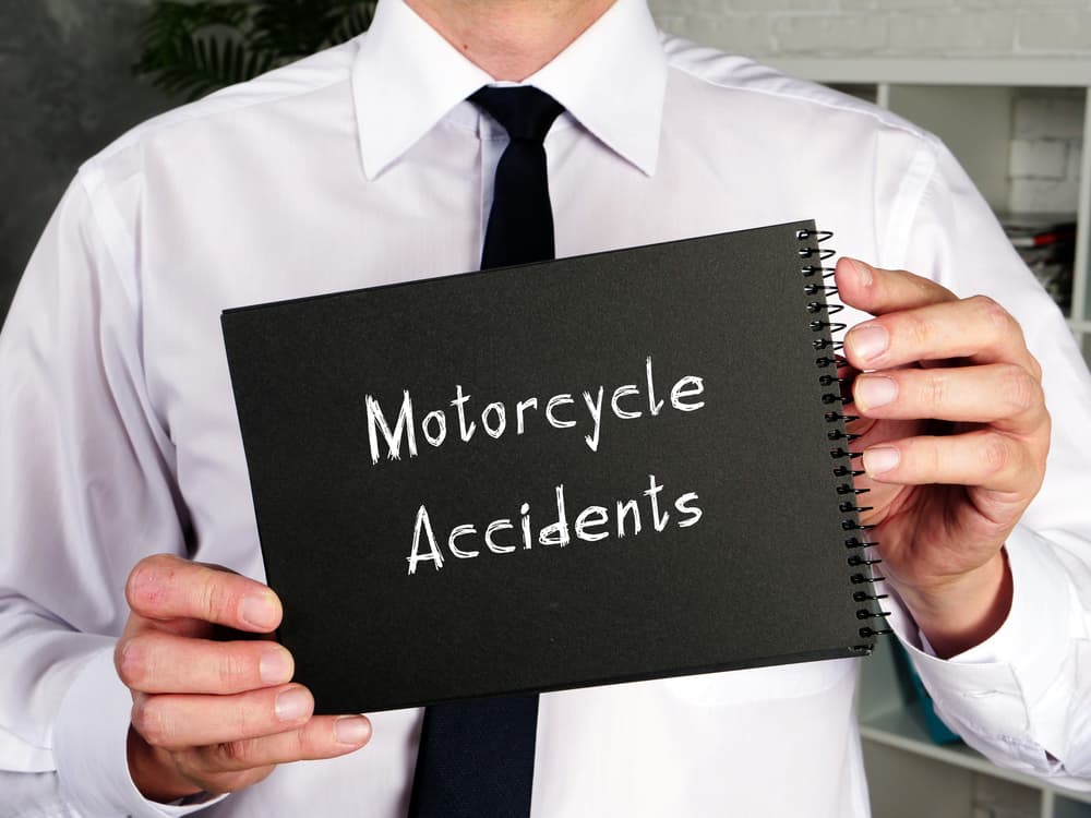 A man displays a notebook labeled 'motorcycle accidents'.